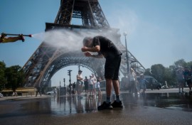 A municipal employee sprays water to cool off tourists in front of the Eiffel Tower in Paris, on July 2, 2025, as a heatwave hits France