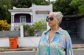 Gloria Cuevas poses in front of her former house in Rincon, Puerto Rico, which has been converted into an Airbnb