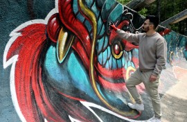 Street artist Kerim Musanovic puts the finishing touches to touches to a painting on the former Olympic bobsled track at Mount Trebevic, near Sarajevo