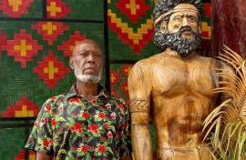 Head chief of the volcanic island of Ambrym, George Bumseng, stands next to a wooden statue in the Vanuatu capital of Port Vila on July 24, 2025