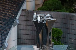Two yellow-crested cockatoos resting atop a statue in Hong Kong Park