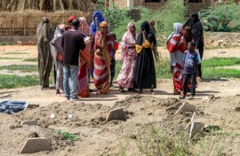 Bereaved relatives gather by the makeshift graves, waiting for the chance to give their loved ones a proper burial