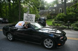 Protestors holding signs drive past the home of John Bolton, President Donald Trump's former national security adviser