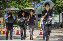 People shield themselves from the hot sun with umbrellas in Tokyo on August 27, 2025