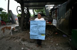 Juana Fuentes, 54, holds a sign addressed to President Nayib Bukele calling for the release of her son Nelson Antonio Fuentes, 23, imprisoned since April 2022