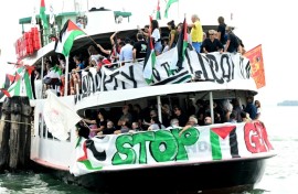 People aboard a boat wave Palestinian flags as they arrive to take part in a demonstration in support of Gaza at the Venice Lido
