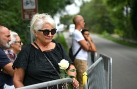 A woman holds a white rose as she waits for the hearse carrying the body of Giorgio Armani