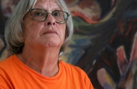 Roberta Hill, residential school survivor from the Mohwak Institute, poses next to a painting by Robert Gary Miller, also a survivor of the Mohawk Institute, during the site's unveiling as a museum in Brantford, Ontario on September 30, 2025