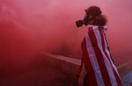 A protester stands in the haze from a smoke grenade outside of a downtown Portland U.S. Immigration and Customs Enforcement (ICE) facility