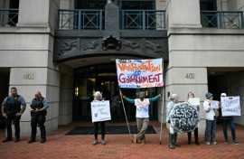 Demonstrators protest outside of the Albert V. Bryan United States Courthouse ahead of the arraignment of former FBI director James Comey