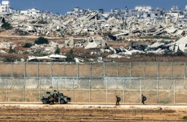Israeli army soldiers walk towards an armoured vehicle at a position along the border fence with the Gaza Strip in southern Israel