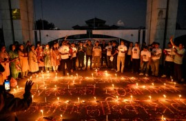 Nepalis lit candles outside the fire-damaged parliament building on Thursday, one month after anti-corruption protests toppled the government and left dozens dead