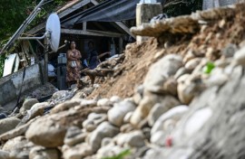 A woman looks at a damaged house in Manay on October 11, 2025, after two powerful quakes struck off the southern Philippines on October 10