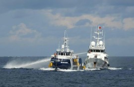 This handout photo taken and released on October 12, 2025 by the Philippine Coast Guard shows a China Coast Guard ship (R) deploying water cannon as a Philippine Bureau of Fisheries vessel (L) is seen alongside during an incident near Thitu island in disputed waters of the South China Sea
