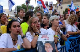 Des Israéliens brandissant des portraits d’otages israéliens encore retenus à Gaza attendent leur libération sur la place des Otages à Tel-Aviv, tôt le 13 octobre 2025
