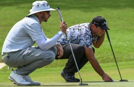 Patrick Reed (right) and fellow American John Catlin line up putts during the first round of the International Series Philippines on Thursday