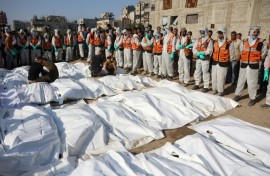 Civil Defense members stand by after laying out body bags containing the remains of members of the Shahebar family, who were buried in temporary graves, as they are brought to a cemetery in Gaza City