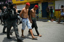 Police officers escort suspects arrested during the raid