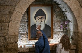 Pilgrims in front of a portrait of Saint Charbel at the monastery of Saint Maron in Lebanon's mountain village of Annaya