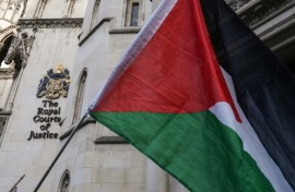 A Palestinian flag held up by protesters outside the London appeal court where the Palestine Action case is being heard
