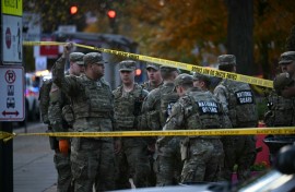 National Guard soldiers stand behind crime scene tape at a corner in downtown Washington where two National Guard soldiers were shot just blocks from the White House