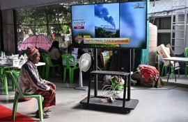 A displaced resident watches the news at an evacuation center in the Thai border province of Surin on December 11, 2025