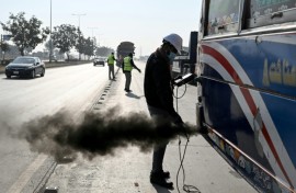 A technician examines a vehicle to test its emissions on road, at a checkpoint on the outskirts of Islamabad