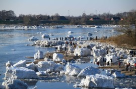 Onlookers make their way through large chunks of ice washed up along the banks of the Elbe river near Geesthacht, northern Germany, on January 19, 2026.