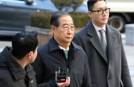 Former South Korean prime minister Han Duck-soo (C) arrives at the Seoul Central District Court for his first sentencing trial in the insurrection case in Seoul on January 21, 2026
