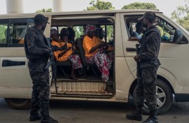 Security officers stand guard next to a bus carrying freed worshippers in northern Nigeria, where gunmen kidnapped Christians in coordinated attacks on three churches in January