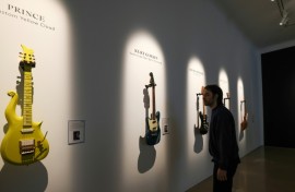 A visitor looks at Prince’s Andy Beech custom Yellow Cloud guitar (L) and Kurt Cobain’s 1966 Fender Mustang guitar ahead of an auction at Christie’s