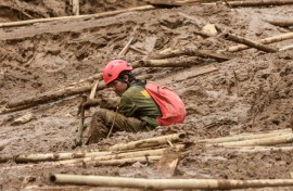 A rescuer rests as they search for victims buried by a landslide in Pasirlangu village