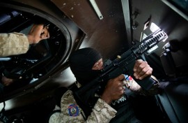 A Haitian police officer aims his weapon out a window of an armored vehicle during a patrol in downtown Port-au-Prince in January 2026