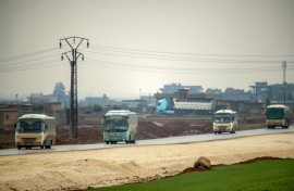 Buses in a US military convoy transporting Islamic State group detainees being transferred to Iraq from Syria