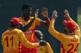 Zimbabwe's Blessing Muzarabani (2L) celebrates with teammates after taking the wicket of Oman's captain Jatinder Singh