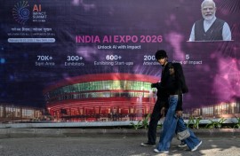Commuters walk past a billboard for an AI Expo in New Delhi
