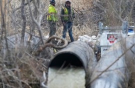 Emergency workers look on as raw sewage flows out of a drainage pipe into the C&O Canal near Cabin John, Maryland, after more than 200 million gallons of wastewater spilled into the Potomac River