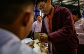 Military chief Min Aung Hlaing (back C) watches a voter ink their finger as he visits a polling station during the final phase of Myanmar's general election in January
