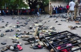 Fans stand next to abandonned shoes and a fallen barrier outside M. Chinnaswamy Stadium