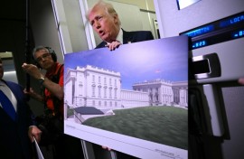 US President Donald Trump holds a rendering of the East Wing modernization as he speaks to reporters aboard Air Force One