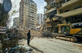 A bulldozer clears the rubble from the site of an Israeli airstrike as people return to Beirut's southern suburbs