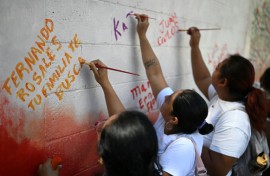 Esmeralda Rosales writes a message addressed to her missing brother, Fernando Rosales, during the inauguration of a mural in tribute to disappeared people, at the University of El Salvador, in San Salvador, on March 19, 2026