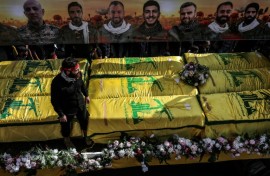 Coffins sit on a trailer beneath portraits of Hezbollah fighters killed in Lebanon by Israel before a 10-day ceasefire was agreed