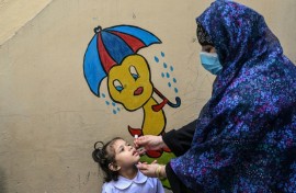A healthcare worker administers polio drops during a door-to-door poliovirus eradication campaign in Lahore
