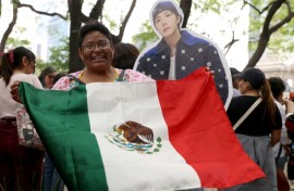 Una mujer muestra una bandera de México junto a una figura de cartón de J-Hope, cantante surcoreano de K-pop del grupo BTS, durante una reunión de fans en la Ciudad de México el 3 de mayo de 2026.