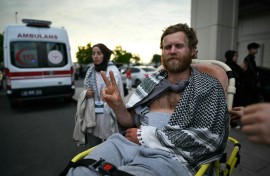 A member of the Global Sumud Flotilla arrested and deported by Israel gives the V-sign as he is brought out of a terminal at Istanbul Airport
