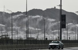 A police car drives past water-mist fans in Mecca ahead of the hajj pilgrimage when temperatures could reach 47 degrees Celsius