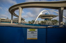 A closed construction area is seen near The SkyLink Automated People Mover line and the Theme Building and Air Traffic Control Tower at Los Angeles International Airport