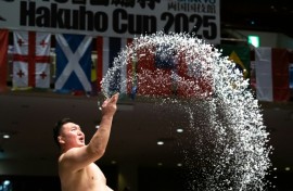 Sumo wrestlers throw salt on the dohyo to drive away evil spirits