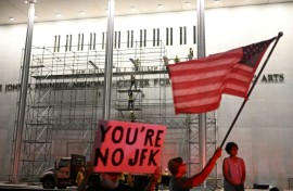 Protesters wave a US flag and hold a sign reading 'You're no JFK' as workers build scaffolding at the Kennedy Center ahead of the removal of Donald Trump's name